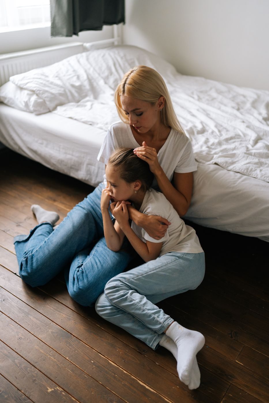 Mãe abraçando a filha no chão do quarto