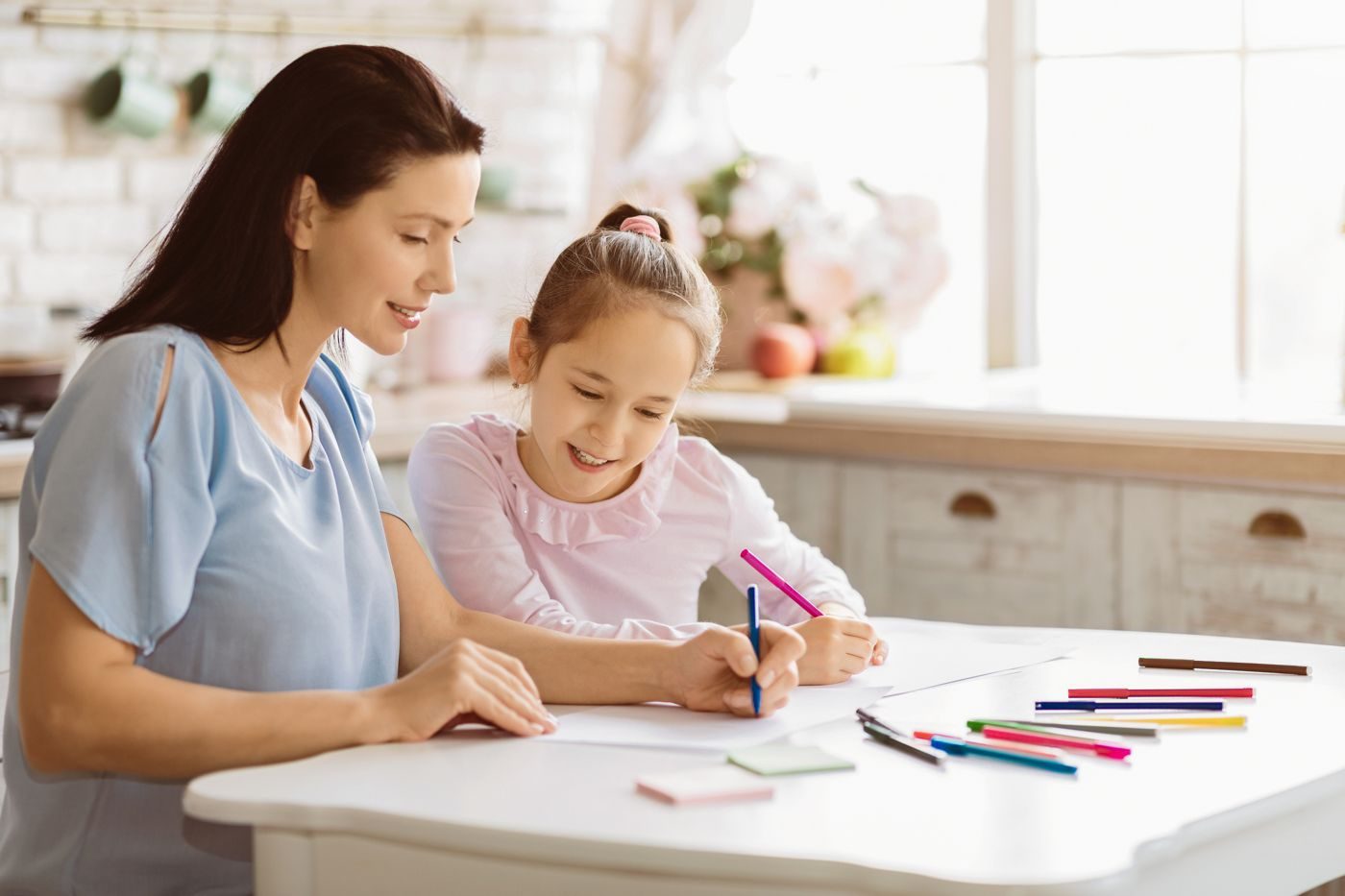 Mãe e filha desenhando juntas na mesa da cozinha