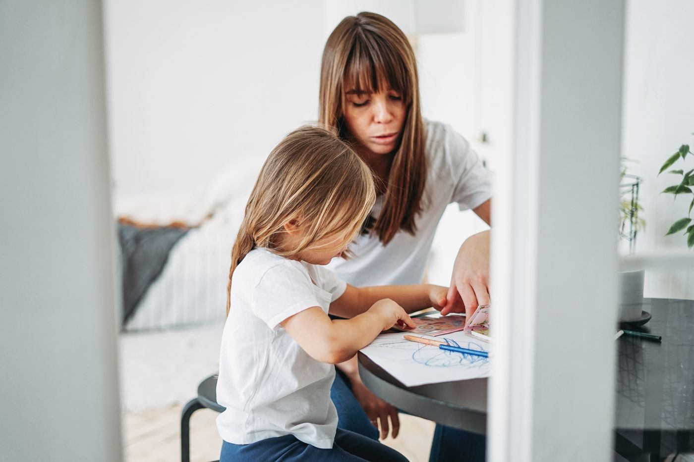 Mãe ajudando a filha a desenhar no papel